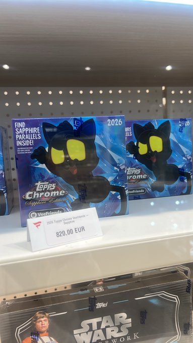 A store shelf displaying 'Topps Chrome Sapphire Edition 2026' trading card boxes featuring a black cat mascot, priced at 820.00 EUR, with Star Wars merchandise below.