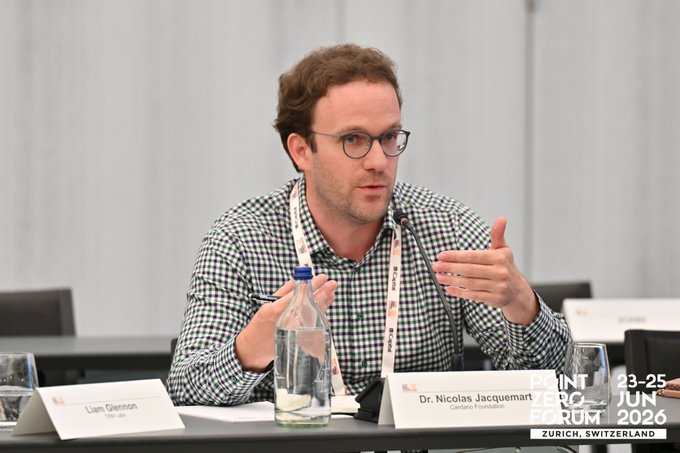 Dr. Nicolas Jacquemot, Co-head of Cardano Foundation, speaking and gesturing at the Point Zero Forum in Zurich, Switzerland, with Liam Glennon of TBA Labs seated to his left.