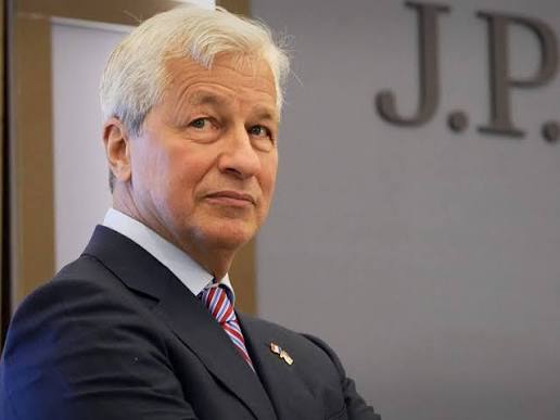 The image features a man dressed in a suit, standing against a gray background with a J.P.P. building behind him. He appears to be looking off into the distance or posing for the camera. The text "Major Update I'm officially leaving crypto to go work at JPMorgan Chase" is visible in the image as well. This suggests that the man might have recently left his position in the cryptocurrency world and is now working at a traditional financial institution like J.P. Morgan Chase, possibly focusing on the crypto space or looking for opportunities to invest in it.