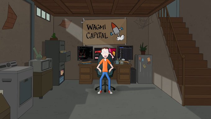 A cartoon illustration of a person with glasses sitting at a desk with multiple computer monitors showing charts, beneath a banner reading 'WAGMI CAPITAL' with a rocket graphic, in a basement-like room.