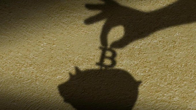 A creative shadow photograph showing a cat-shaped shadow appearing to balance on its head, with a hand shadow nearby, on a beige textured surface.