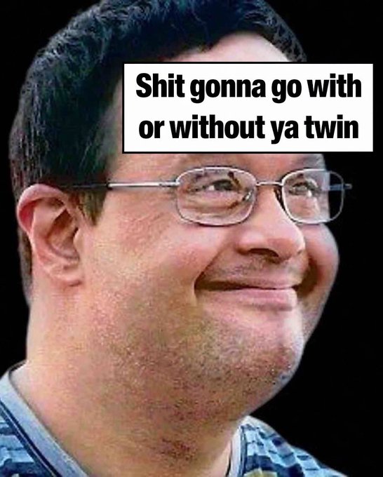 The image features an older man wearing glasses with a smile on his face. The caption reads " Shit Gonna Go With or Without ya Twin" which seems to be a reference to the current situation of the world, possibly related to the spread of COVID-19. The man's facial expression and the context behind the caption suggest that he is happy despite the challenging circumstances.