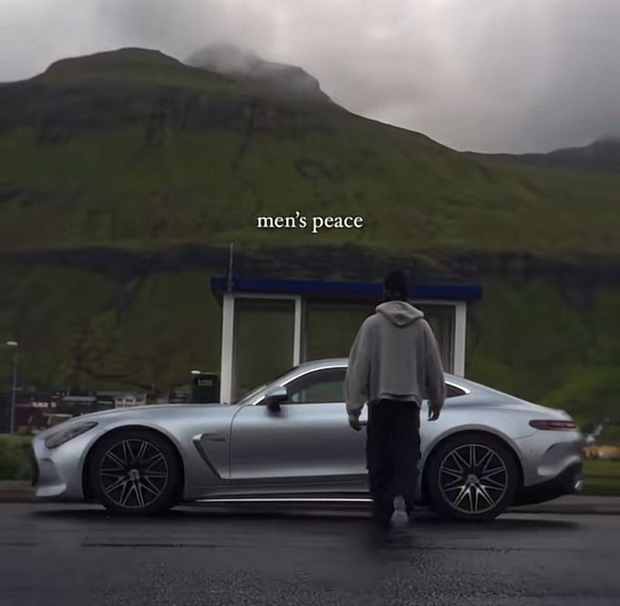 An atmospheric, moody shot of a person in a hoodie standing beside a silver Mercedes-AMG GT sports car in front of misty green mountains, with the text 'men's peace' overlaid.
