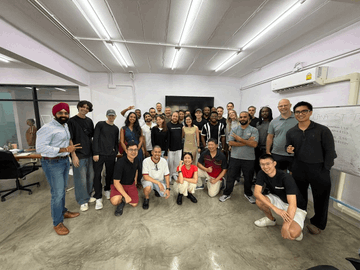 A group photo of approximately 20 people gathered in an office setting, posing together for a team picture.