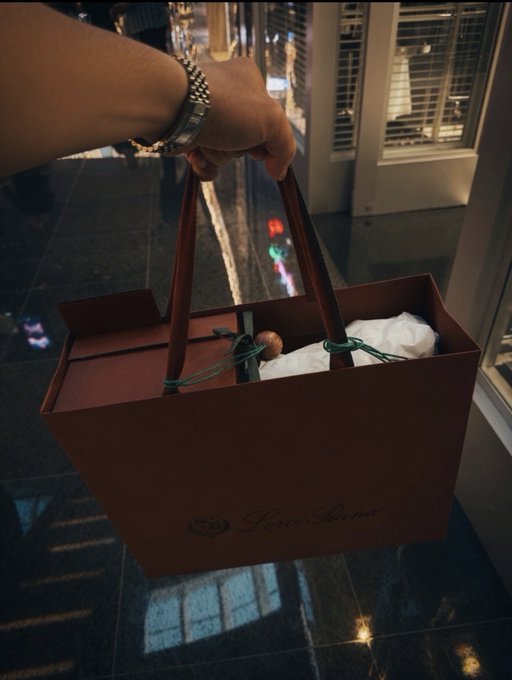 The image shows a person holding a brown paper bag that has "Love" written on it. The bag appears to be filled with items, possibly gifts for someone else. The photo also includes text that reads "Good night GN This weekend is for bear energy only Degens don't cash out, they cash out just stay locked in with the loudest or get drowned out".