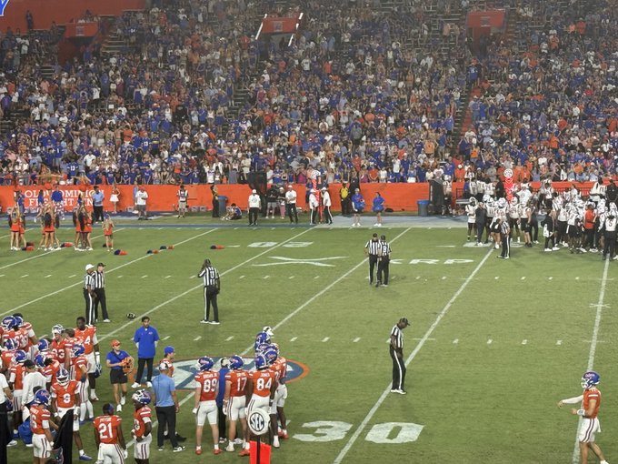 A college football game scene with Florida Gators players on the field facing the crowd at a stadium, with SEC and "30" yard line markings visible