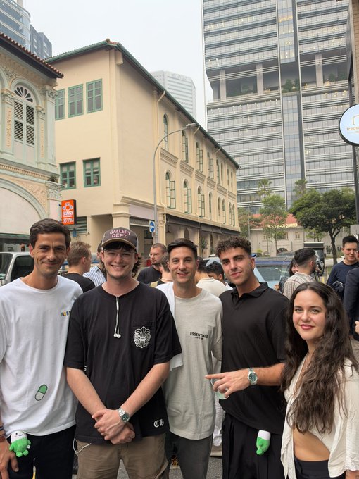 A group of five friends smile for a photo on a city street in front of modern high-rise buildings, with the man second from right wearing a "PERRY DEPAR" cap and another in a "PROSPERITY" shirt. The casual gathering among young crypto/pump enthusiasts visually reinforces the post's boast about trading on Pumpfun and seeking advice at an FnF @Pumpfun meetup.