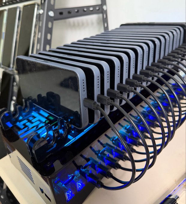A row of smartphones connected to cables, charging on a multi-port dock with blue indicator lights.