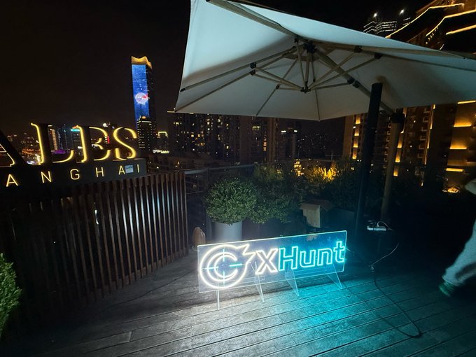 A rooftop scene at night in Shanghai features a 'JIES SHANGHAI' illuminated sign, a 'CxHunt' neon light, a large white umbrella, and a city skyline in the background.
