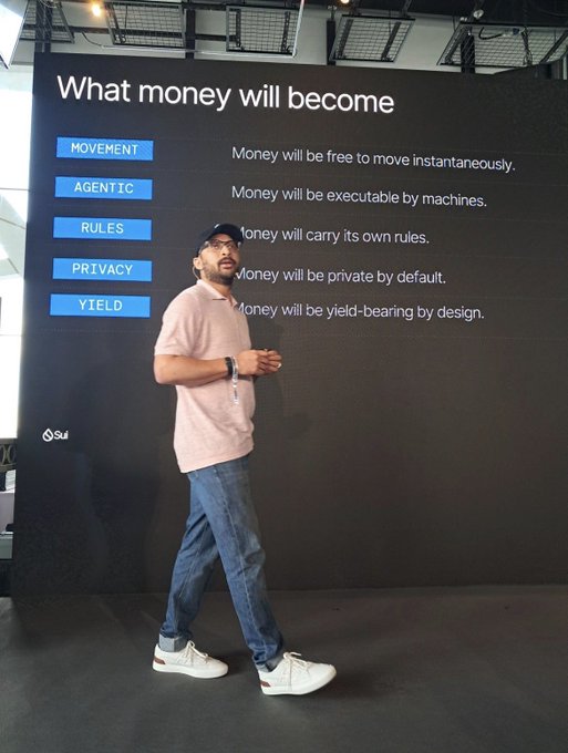 A man in a pink shirt and cap stands in front of a presentation slide titled 'What money will become,' listing principles like Movement, Agentic, Rules, Privacy, and Yield, with a Sui logo in the corner.