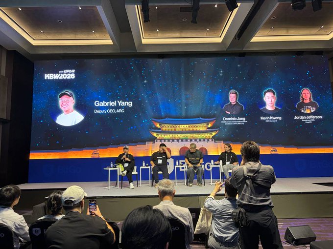 A panel discussion at the HBW2026 (Hong Kong Blockchain Week) conference with speakers including Gabriel Yang (Deputy CEO, AIOZ), Dominic Jing, Kevin Kwong, and Jordan Jefferson seated on stage before an audience.