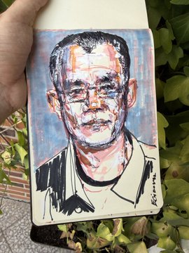A painted portrait of a rugged man in a collared shirt displayed on a small canvas held outdoors near green foliage.