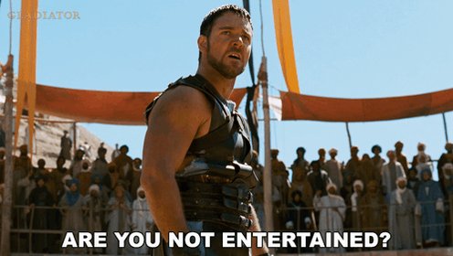 The image features a man dressed as a Roman soldier standing in an arena with a crowd of people behind him. The caption reads "Are you not entertained?" which seems to be a reference to the movie "The Gladiator".