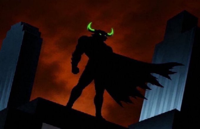 A dark silhouette of a muscular figure with glowing green eyes and horns wearing a flowing cape, standing on a rooftop against a deep red sky between two skyscrapers.