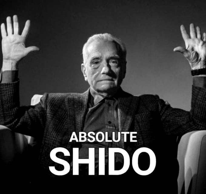A black-and-white photo of an older man with white hair raising both hands with palms open, captioned 'ABSOLUTE SHIDO' in bold white text.