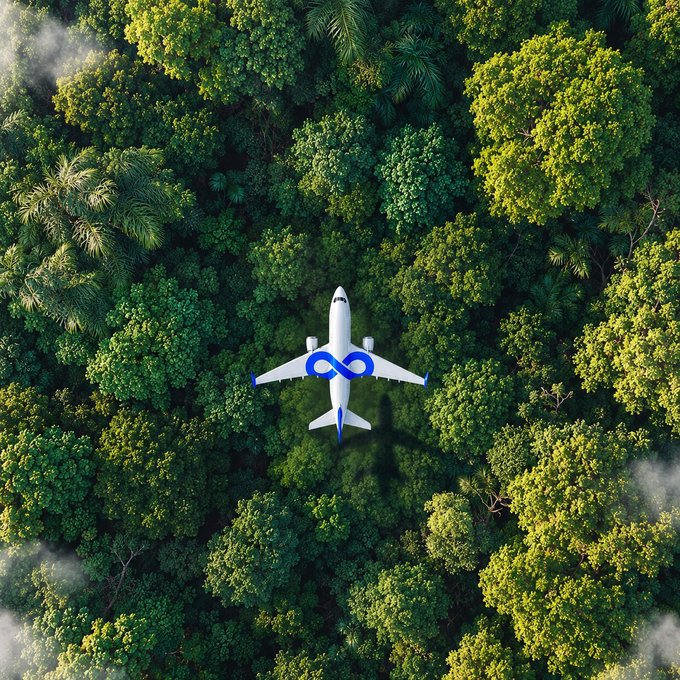 An aerial view shows a white and blue airplane flying over a lush green forest canopy, with the airline's infinity-style logo visible on its wing.