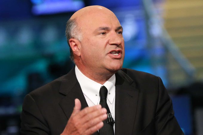 Kevin O'Leary, shown speaking at what appears to be a conference, argues that the CLARITY Act is delayed rather than dead and predicts Congress will revisit crypto market structure legislation in the first half of next year following the midterm elections.