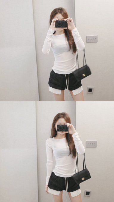 A young woman takes mirror selfies in two stacked frames, wearing a fitted white long-sleeved top, black shorts over white biker shorts, and carrying a black shoulder bag while holding a camera.
