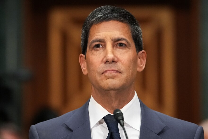 A serious-looking man in a dark blue suit and tie speaks at a microphone in what appears to be a formal government hearing setting. The image likely depicts a Federal Reserve official or central banker, connecting to the post's anticipation that his rate-cutting decision will trigger a surge in Bitcoin and altcoin prices.