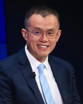 A smiling man in a dark suit and light blue tie, wearing glasses, appears on what looks like a stage or panel setting. The image likely depicts Changpeng Zhao (CZ), the former CEO of Binance, whose recent burn of 1.1 billion in donated memecoins is referenced in the accompanying post.