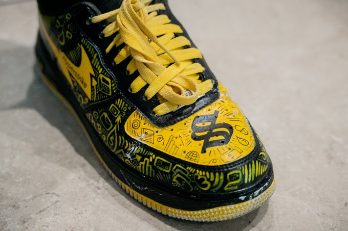 This image shows a custom black and yellow Nike Air Force 1 shoe featuring "Hyperstrike" text and various crypto-related doodles, fitting the "drip" mentioned in the post. The shoes are likely worn by someone at the @SuperteamBLKN Solana Summit Serbia.