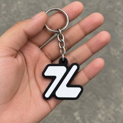 A hand holds a black and white rubber keychain featuring the number '76' and attached to a silver metal ring.