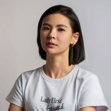 A portrait of a woman with short dark hair wearing a white t-shirt with the text 'Lady First Forward.'