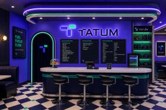 A dimly lit bar or lounge interior with neon blue lighting, featuring a counter with stools, chalkboard menus, and the sign 'TATUM' illuminated on the back wall.
