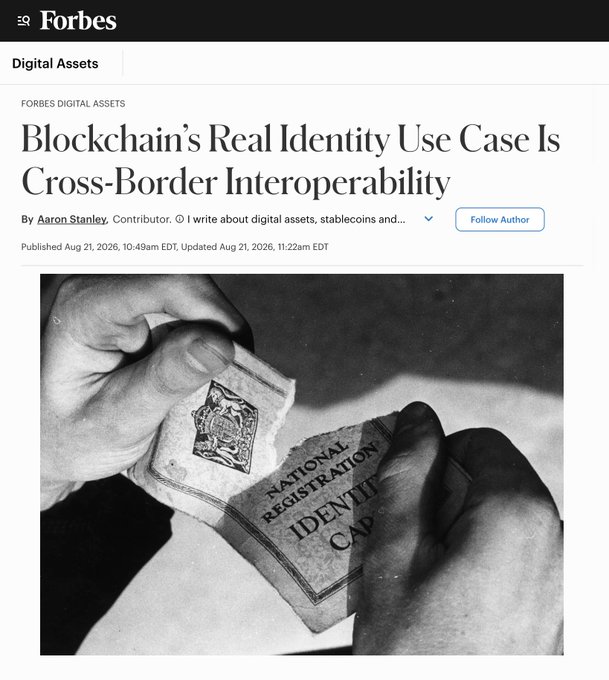 A Forbes Digital Assets article titled 'Blockchain's Real Identity Use Case Is Cross-Border Interoperability' by Aaron Stanley, published August 21, 2026, featuring a black-and-white image of hands holding a National Registration Identity Card.