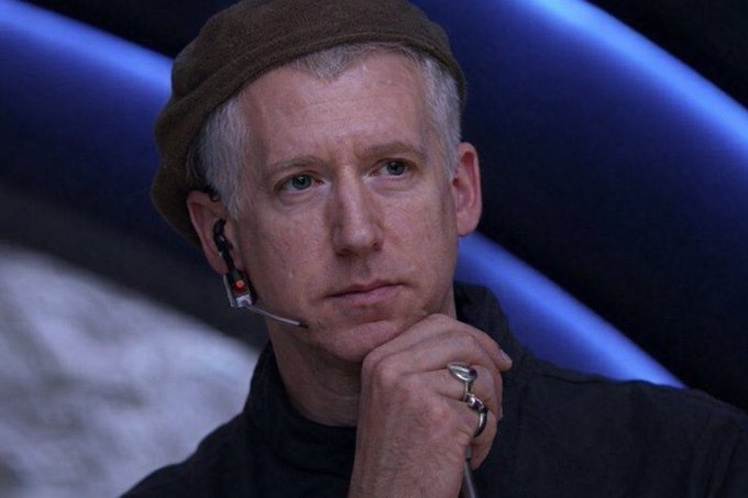 A man with gray hair wearing a dark beanie and a headset microphone rests his chin on his hand, appearing deep in thought against a blue-lit backdrop, suggesting a contemplative moment during a tech talk or podcast about blockchain chains and their strategic paths, including references to Monad.
