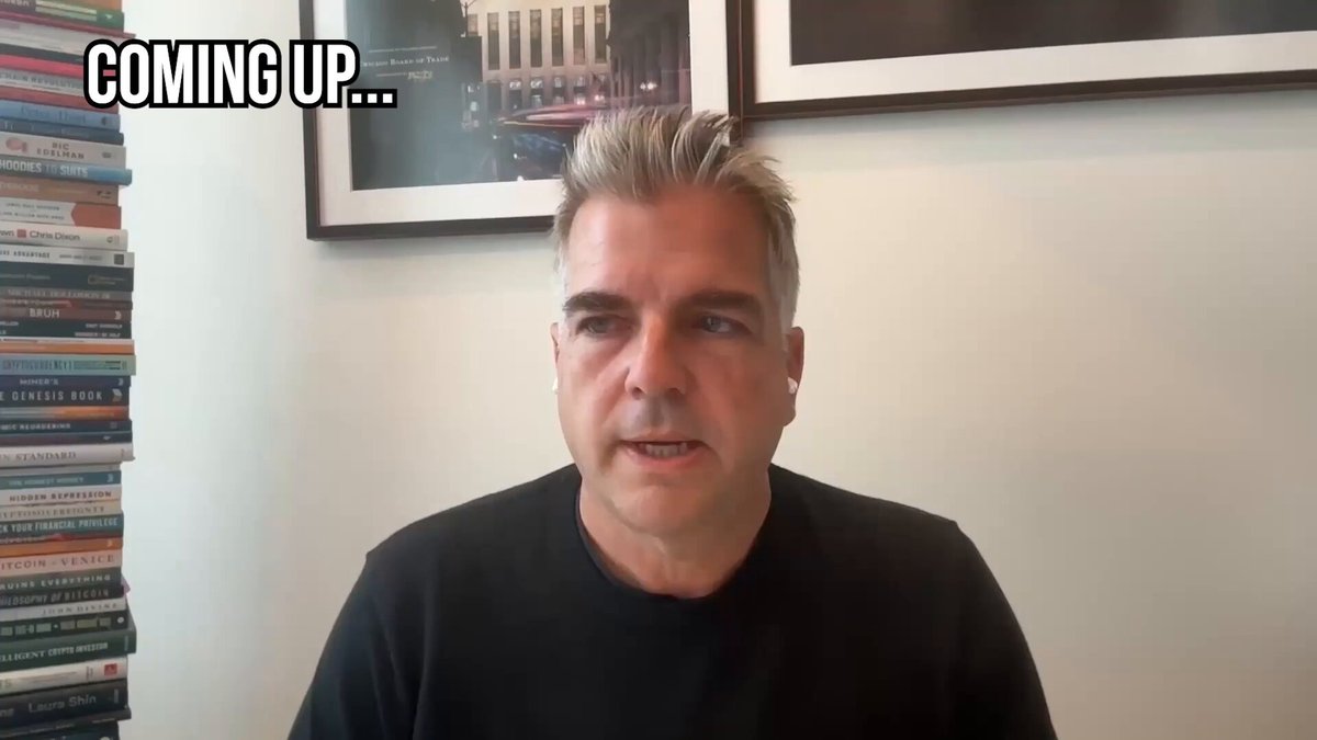 The image shows a man sitting at a desk with stacks of books behind him, looking serious or sad as he appears to be talking about something important over the phone. The text overlay on the image reads "coming up...", but there are no other words visible in this part of the image.