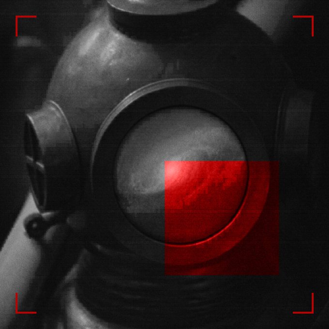 A dark, cinematic black-and-white image of a gas mask with a red-tinted lens and red targeting bracket marks in the corners, giving it a surveillance or sci-fi aesthetic.