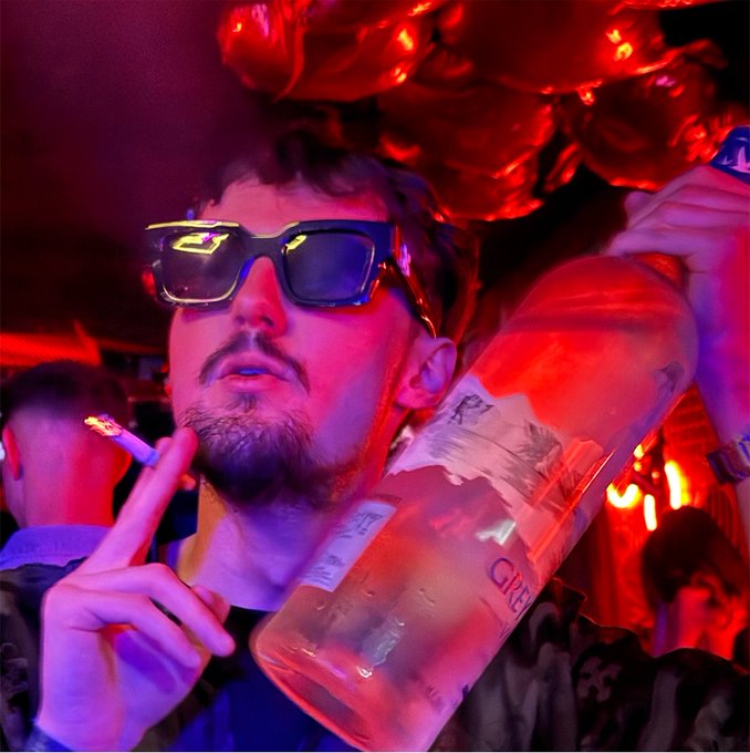 A man wearing sunglasses holds a large empty bottle and a cigarette at a club, with red balloons in the background—the opulent, party-hard scene embodies the "Memecoins changed my life" lifestyle, where viral crypto gains fund flashy nights out.