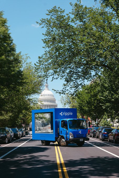 A blue Ripple-branded delivery truck with "On the road to Clarity" written on its side drives down a tree-lined Washington D.C. street with the U.S. Capitol building visible in the background. The image symbolizes Ripple's push for regulatory clarity in crypto, tying into the post's bullish outlook for XRP.