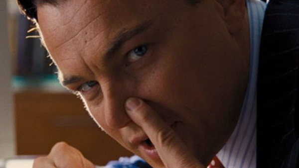 A close-up portrait of Leonardo DiCaprio in a pinstripe suit with his finger pressed against his nose.