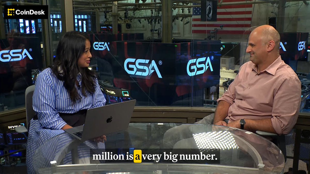The image shows a CoinDesk interview at the Nasdaq studio featuring host Jenn Sanasie interviewing Mark L. Greenberg (Mark LG) of Payward, the parent company of Kraken crypto exchange, with GSA branding visible in the background and subtitles reading "million is a very big number." The scene captures the exclusive discussion about Nasdaq's $100 million investment in Payward and the growing mainstream acceptance of tokenization in crypto infrastructure.