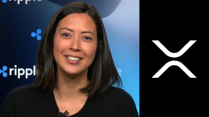 A woman stands in front of a Ripple branded backdrop next to the XRP logo, accompanying news that the XRP Ledger has reached a record high of over 8.4 million accounts.