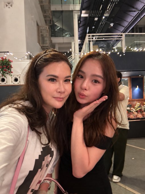 Two women posing for a close-up selfie in what appears to be an indoor venue with string lights.