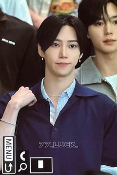 A young man with dark hair wearing a navy shirt over a striped collar raises his fist near his face at what appears to be an airport. A watermark reads "77_LUCX" and a "MENU" button with search and icons is visible in the corner, matching the hashtags for Zhang Jiahao (장지아하오/张家豪) of Alpha Drive One.