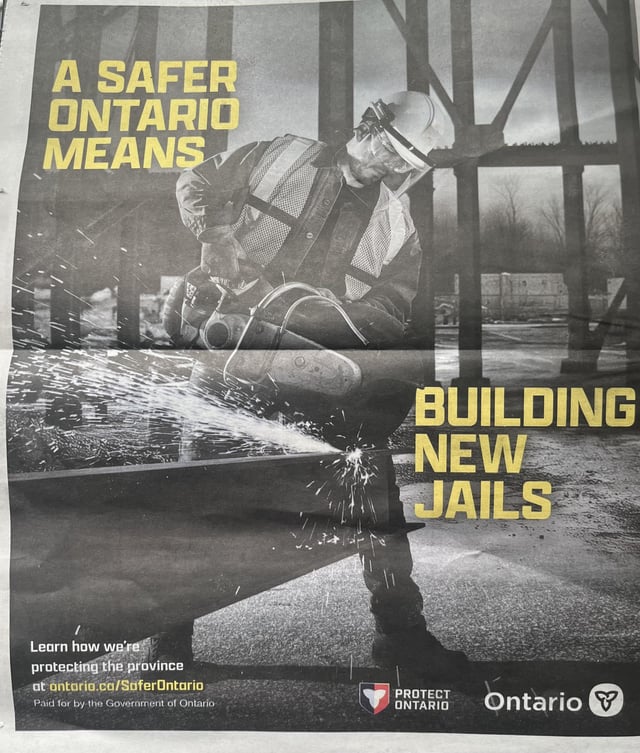 The image features a poster with an advertisement for a campaign against building new jails, which has been posted by the Ontario government. The poster includes a photo of a man wearing a hard hat and safety gear while working at a construction site. The text on the poster encourages people to learn more about the issue and share their thoughts on social media using the hashtag #buildingnewjails.