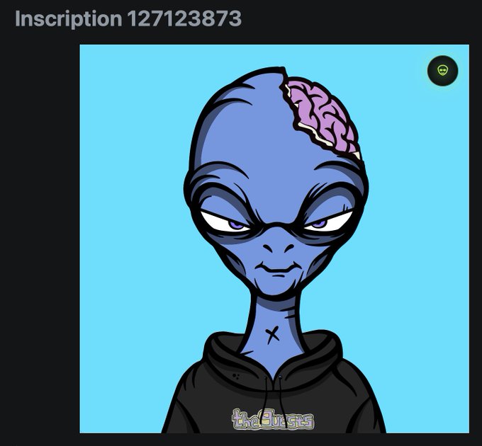 A cartoon blue alien with an exposed pink brain wears a black hoodie, with "theduens" text on the chest and "Inscription 127123873" displayed above, fitting the meme's celebratory tone as the Ordinals inscription count surpasses 600 in collectors' wallets.