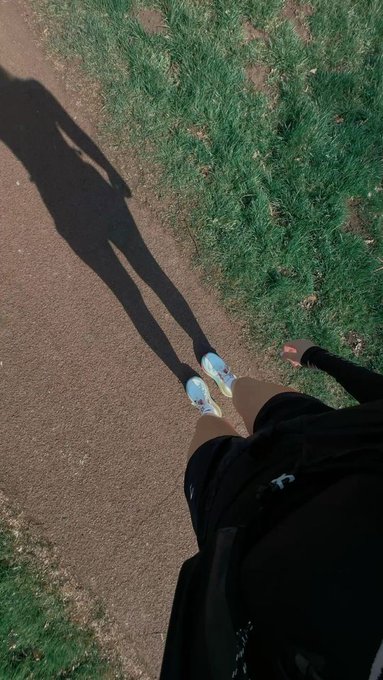 urn-shaped shadow on a dirt path, with a person's feet visible and a backpack nearby.