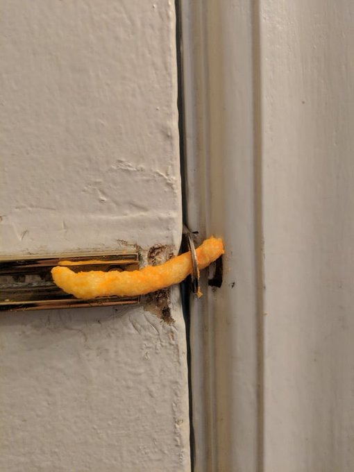 An orange cheese puff snack is wedged through a door latch mechanism, humorously illustrating Bitcoin's difficulty breaking through the $80k resistance level—just like the snack getting stuck in the gap.