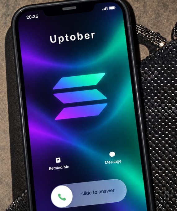 A smartphone displaying an incoming call screen with the caller name 'Uptober' against a purple and green aurora-themed background, featuring Solana's logo and options to Remind Me, Message, or slide to answer.