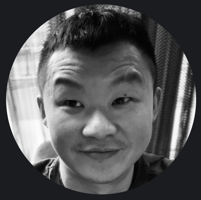 A black and white circular profile photo of an Asian man with short dark hair smiling at the camera.