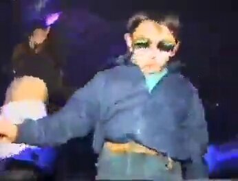 The image shows a young boy wearing sunglasses, standing against a dark background with blue lights. The boy appears to be dancing or performing some sort of action, possibly at an event like a concert. There are two people visible in the scene - one person is behind the boy and another person can be seen on the left side of the image. The text "NEAR made intents a consumer UX conversation." suggests that there might be a discussion about user experience or a related topic, possibly related to the event where the boy is performing.