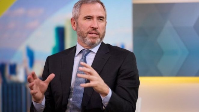 The image features a man dressed in a suit and tie giving a speech or presentation. The text "BREAKING: Ripple CEO Brad Garlinghouse says XRP is positioned to play a major role in the future of U.S. financial infrastructure" suggests that Ripple, a cryptocurrency exchange, has been making waves in the financial world. The man's position behind a podium and his gestures indicate he is addressing an audience or participating in a panel discussion on this topic.