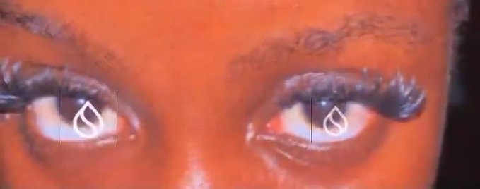 An extreme close-up focuses on a person's eyes with reddish-orange lighting and digital teardrop graphics superimposed over each eye.