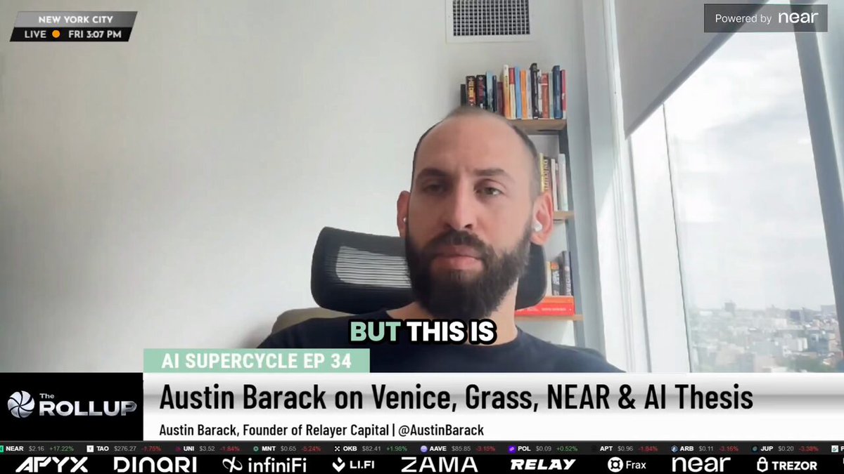 The image shows a man sitting in front of a window, with a TV screen behind him displaying an interview or news segment featuring Austin Barack. The TV screen also displays text related to the topic of the interview, which seems to be about Austin's thesis on grass and its valuation.