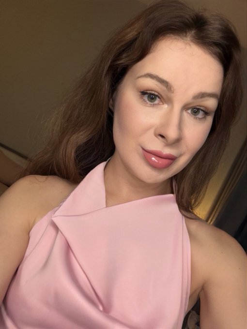A close-up portrait shows a woman with long brown hair wearing a sleeveless pale-pink halter-style top.